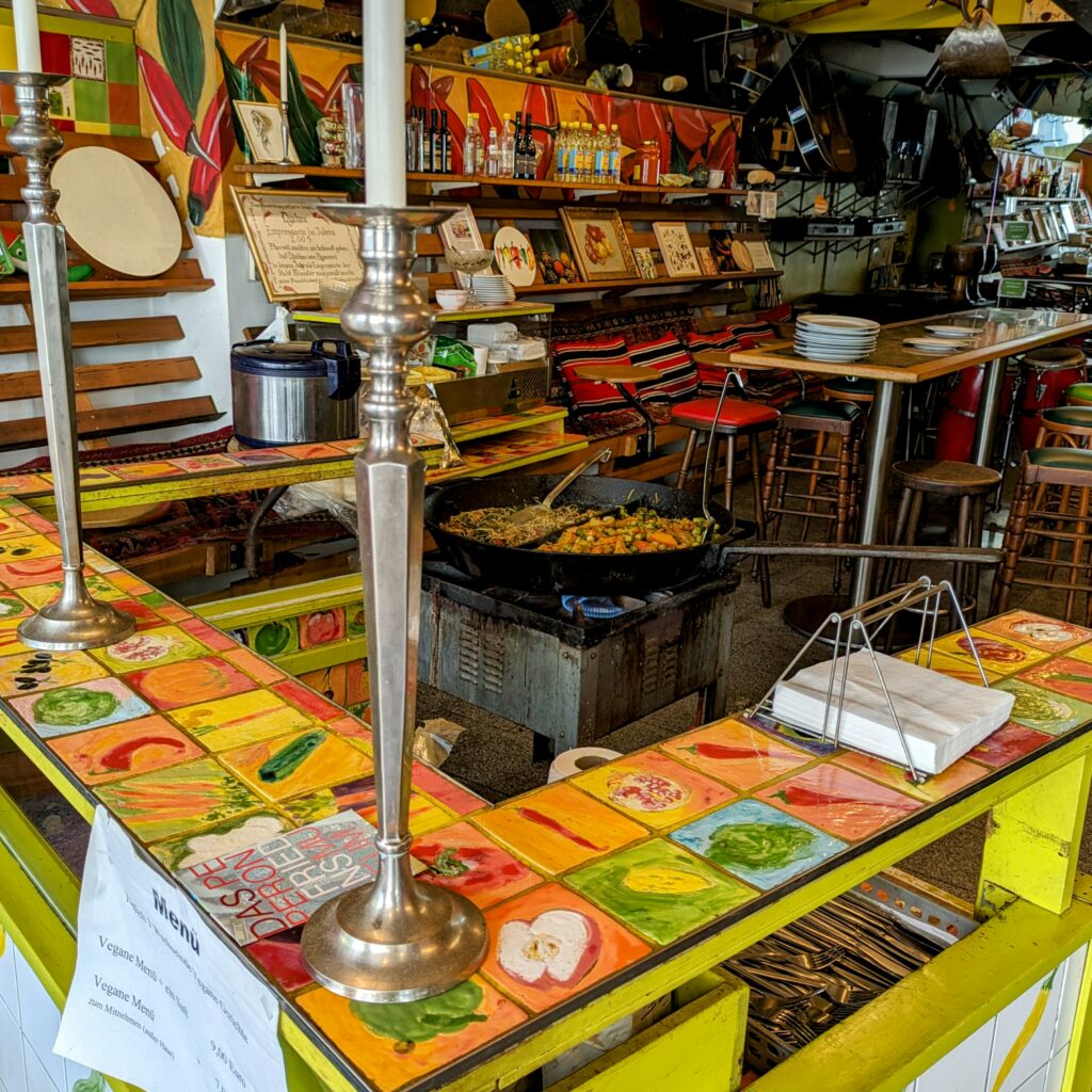 Die Peperoni ist definitiv mehr als nur ein Restaurant, das spürt man schon beim Anblick des Ladens. Die Identität des Restaurants ist leicht an den metergroßen Peperonis vor dem Laden zu erkennen. Doch das Peperoni sieht sich selbst auch als Friedensmuseum. Durch unzählige Fliesenbilder und Kacheln, die die Wände schmücken, sorgt Inhaber Djahan nicht nur für ein optisches Highlight, sondern erzählt auch seine bewegende Geschichte und die der verschiedenen Menschen, die ihn in seinem belebten Leben begleitet haben.