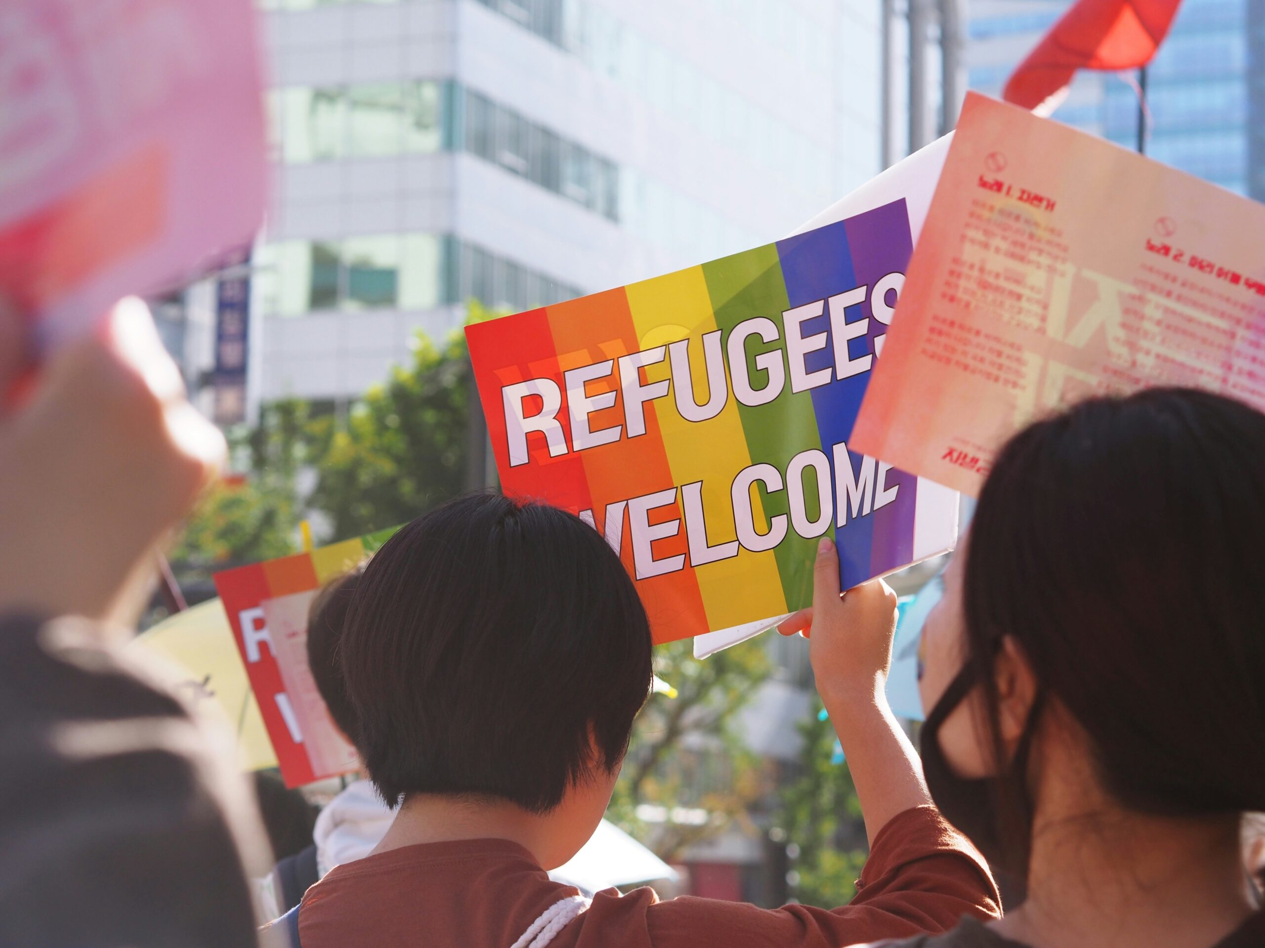 Flüchtlinge und Kriminalität. Das Bild zeigt demonstrierende Menschen mit Regenbogenplakaten.