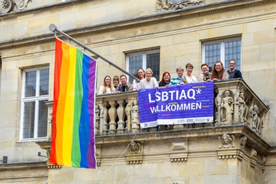 Münster setzt Zeichen für Akzeptanz am IDAHOBIT Regenbogenflagge am Stadtweinhaus Anlässlich des Internationalen Tages gegen Homo-, Bi-, Inter*- und Transfeindlichkeit (IDAHOBIT) hat die Stadt Münster am Freitag, den 17. Mai, ein starkes Zeichen für mehr Akzeptanz von sexueller und geschlechtlicher Vielfalt gesetzt. Um ihre Unterstützung zu zeigen, wurde das Stadtweinhaus mit der Regenbogenfahne beflaggt. Diese Aktion war eine Initiative des Amtes für Gleichstellung und zielte darauf ab, das Bewusstsein für die Rechte und die Akzeptanz der LSBTIQ-Community zu stärken.