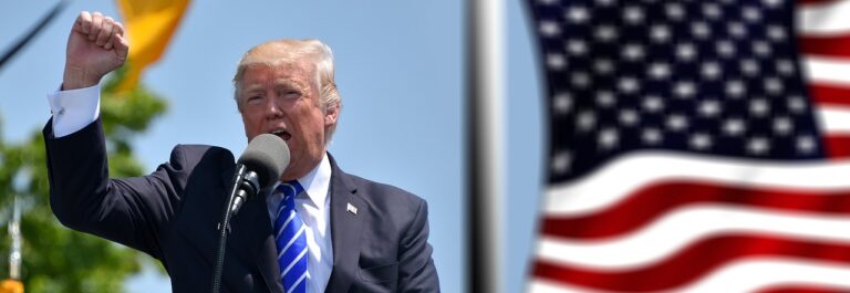 Donald Trump präsentiert im Weißen Haus ein Schaubild seiner angekündigten „Reciprocal Tariffs“. Auf Importe aus der Europäischen Union sind laut seinen Plänen neue Zölle von 20 Prozent vorgesehen. Die USA erheben ab dem 5. April pauschal 10 Prozent Zoll auf Einfuhren aus allen Ländern; für Staaten mit hohen Handelsüberschüssen gegenüber den USA – darunter Deutschland – gelten sogar höhere Strafzölle. Für die EU bedeutet dies einen Aufschlag von 20 Prozent auf praktisch alle Warenexporte in die Vereinigten Staaten. Dieses massive Zollpaket markiert einen neuen Höhepunkt in Donald Trumps protektionistischer Handelspolitik und sorgt weltweit für Unruhe. Nun stellt sich die Frage, was diese US-Zölle für die deutsche Wirtschaft bedeuten – insbesondere für die Region Münster und das Münsterland, deren Unternehmen stark exportorientiert sind. US-Zölle setzen Deutschland und Europa unter Druck Die neuen Zollmaßnahmen der USA drohen einen transatlantischen Handelskonflikt auszulösen. EU-Kommissionspräsidentin Ursula von der Leyen stellte bereits Gegenmaßnahmen in Aussicht und betonte, man werde europäische Interessen „schützen“. Auch Bundeskanzler Olaf Scholz fand deutliche Worte und nannte Trumps Schritt „einen Anschlag auf [die] Handelsordnung, die Wohlstand überall auf dem Globus geschaffen hat“. Zahlreiche Experten warnen vor einem Handelskrieg: Außenhandelsverbände rechnen fest mit Gegenzöllen der EU, was Exportfirmen Umsatzeinbußen bescheren und in der Folge Produktion und Arbeitsplätze kosten könnte. „Ich sage es ganz offen: Das werden wir spüren“, kommentierte Dirk Jandura, Präsident des Bundesverbandes Großhandel, Außenhandel, Dienstleistungen (BGA). Vor allem Deutschlands exportstarke Branchen geraten ins Visier. So gelten ab sofort zusätzliche 25 Prozent Zoll auf alle ausländischen Autos und Autoteile, die in die USA eingeführt werden. Die deutsche Automobilindustrie reagierte entsetzt: Diese Maßnahmen seien ein „massiver handelspolitischer Einschnitt“ und eine „massive Belastung“ für Unternehmen und globale Lieferketten, erklärte Hildegard Müller, Präsidentin des Verbands der Automobilindustrie (VDA). 2024 wurden fast 450.000 Fahrzeuge aus deutscher Produktion in die USA exportiert – der wichtigste Auslandsmarkt für hiesige Autobauer. In Trumps zweiter Amtszeit droht dieser Absatz nun einzubrechen. Viele Nicht-EU-Staaten trifft es sogar noch härter: Für China etwa sieht Trumps Tafel „reciproker“ Zölle einen Aufschlag von 34 Prozent vor, für Vietnam rund 46 Prozent. Auch außerhalb des Industriesektors sind Spannungen spürbar. Die Landwirtschaft dürfte ebenfalls betroffen sein: Trump hat angekündigt, demnächst zusätzliche Zölle auf Agrarimporte in die USA zu erheben. Zwar stehen die konkreten Waren noch nicht fest, doch sollten amerikanische Strafzölle etwa auf europäische Lebensmittel greifen, könnte das auch Exporte aus deutschen Agrarregionen verteuern. Verbraucher in den USA müssen sich ohnehin auf spürbare Preissteigerungen einstellen – und auch deutsche Verbraucher könnten indirekt Auswirkungen zu spüren bekommen, sollte der Handelsstreit eskalieren. Wirtschaftliche Folgen im Münsterland Die Region Münsterland mit der Stadt Münster als Oberzentrum ist traditionell stark exportorientiert und würde von einem transatlantischen Zollstreit nicht verschont bleiben. „Wird der Export durch Trumps Zollpolitik erschwert, trifft das nicht nur Unternehmen mit einem US-Geschäft – solche wohlstandsdämpfenden Maßnahmen schlagen auch auf nachgelagerte Branchen durch“, warnt die Industrie- und Handelskammer (IHK) Nord Westfalen. Anders gesagt: Zulieferbetriebe, Logistik-Dienstleister und sogar der lokale Handel könnten die Folgewirkungen zu spüren bekommen. Ein Überblick, welche Branchen in Münster und im Münsterland besonders betroffen sein könnten: • Maschinenbau und Industrie: In keinem Sektor des Münsterlands sind die USA so wichtig wie im Maschinen- und Anlagenbau. „Im Münsterland träfe Trumps Zollpolitik den Maschinenbau im besonderen Maße – er ist in den Kreisen Warendorf und Steinfurt eine tragende Säule“, betont IHK-Hauptgeschäftsführer Dr. Fritz JaeckelGerade mittelständische Maschinenbauer der Region weisen Exportquoten von teils über 60 Prozent auf. Strafzölle von 20 Prozent auf ihre Produkte könnten diesen Betrieben direkt wehtun und Aufträge gefährden. Viele Spezialmaschinen „Made in Münsterland“ – etwa Verpackungsanlagen, Agrartechnik oder Textilmaschinen – verkauft man bisher erfolgreich nach Nordamerika. Bleiben diese Aufträge aus oder werden sie wegen der Zölle teurer, drohen Umsatzrückgänge in einer Branche, die als Rückgrat der regionalen Wirtschaft gilt. • Automobilzulieferer: Große Automobilwerke gibt es in Münster und Umgebung zwar nicht, doch zahlreiche Zulieferer im Münsterland hängen indirekt am US-Automarkt. Sie liefern Bauteile, Materialien oder Maschinen an deutsche Autobauer und Systemlieferanten. Wenn in den USA weniger BMW, Mercedes oder VW gekauft werden, wirkt sich das entlang der Lieferkette bis ins Münsterland aus. So zählt Nordamerika für einige örtliche Gießereien, Kunststoff- und Elektronikproduzenten zu den wichtigsten Absatzmärkten. Der VDA spricht bereits jetzt von einer schweren Belastung der Branche. Ab dem 2. April gilt zudem ein pauschaler Zollaufschlag von 25 Prozent auf alle importierten Autos in den USA. NRW-Zulieferer – etwa Hersteller von Getriebeteilen, Kabelbäumen oder Sitzen – verlieren dadurch an Preiswettbewerbsfähigkeit. Das Münsterland ist Teil dieses industriellen Netzwerks: Firmen wie diese könnten weniger Aufträge erhalten und im schlimmsten Fall Arbeitsplätze abbauen, sollte der „Zollhammer“ längerfristig auf dem Automobilsektor lasten. • Logistik und Handel: Die Logistikbranche im Münsterland – mit international agierenden Speditionen wie Fiege (Greven) oder großen Lagern entlang der Autobahnen – spürt globale Handelsveränderungen meist unmittelbar. Höhere Zölle dämpfen das Handelsvolumen: Weniger Exporte bedeuten für Speditionen und Frachtunternehmen weniger Aufträge für den Warentransport über den Atlantik. Ein Bielefelder Logistikunternehmer aus der Nachbarregion Ostwestfalen fürchtet bereits eine Eskalation des Handelskonflikts zwischen den USA und China, die das Frachtgeschäft zusätzlich belasten würde. Auch Zollbürokratie und längere Abfertigungszeiten könnten zunehmen, was die Lieferketten komplizierter macht. Münsters Hafen und die Güterbahnhöfe der Region, die für den Export wichtige Drehscheiben sind, würden bei einem Einbruch des US-Geschäfts ebenfalls geringere Umschlagsmengen verzeichnen. Insgesamt steht eine Branche mit vielen Beschäftigten – vom Lkw-Fahrer bis zum Zolldeklaranten – vor ungewissen Zeiten. • Agrar- und Ernährungswirtschaft: Das Münsterland ist eine bedeutende Agrarregion (u.a. Milchprodukte, Fleisch, Getreide), jedoch gehen die meisten hiesigen Agrar-Erzeugnisse nicht direkt in die USA. Dennoch könnte Trumps Zollpolitik Auswirkungen bis auf westfälische Bauernhöfe haben. Sollte Washington etwa EU-Lebensmittel ins Visier nehmen – wie schon 2019 bei Käse und Butter – wären auch Verarbeiter und Lebensmittel-Exporteure aus unserer Region betroffen. Beispielsweise ist nordrhein-westfälische Milchschokolade oder Spezialitäten wie westfälischer Schinken in Übersee beliebt; zusätzliche Zölle würden diese Produkte in den USA verteuern und weniger konkurrenzfähig machen. Die heimische Landwirtschaft spürt zudem indirekt die globalen Preisverschiebungen: Wenn überschüssige europäische Waren wegen US-Zöllen auf den Binnenmarkt drängen, könnten Preise und Absatzchancen für Münsterländer Erzeuger sinken. Der Landwirtschaftsverband warnt vor einem „Dominoeffekt“, der vom transatlantischen Streit ausgehen könnte – vom Exportbetrieb bis zum Familienhof. • Hochschulen und Forschung: Auch die Wissenschafts- und Bildungslandschaft Münsters registriert die veränderte Lage. Die Westfälische Wilhelms-Universität und die Fachhochschule Münster pflegen zahlreiche Partnerschaften in den USA – von Studentenaustausch bis zu gemeinsamen Forschungsprojekten. Ein länger andauernder Handelskonflikt belastet das politische Klima und könnte den akademischen Austausch erschweren. Beispielsweise könnten transatlantische Förderprogramme gekürzt oder Visa-Auflagen strenger werden, was den Personalaustausch beeinträchtigt. Zudem beziehen Hightech-Forschungsbereiche (etwa Nanotechnologie oder Medizintechnik in Münster) spezialisierte Geräte und Materialien teils aus den USA. Wenn diese Importe nun mit 10 Prozent Zoll belegt sind, steigen die Kosten für Forschungseinrichtungen, und Budgets geraten unter Druck. Mittelbar hängt also selbst der Hochschulstandort Münster an offenen Handelsbeziehungen. Universitäts-Ökonomen in Münster beobachten die Entwicklung genau und mahnen, den Dialog mit den amerikanischen Partnern nicht abreißen zu lassen – denn Innovation lebt vom freien Austausch, nicht von Abschottung. Mittel- und langfristige Folgen für den Standort Münster Kurzfristig sorgen Trumps Zölle vor allem für Verunsicherung in der Wirtschaft. Mittel- bis langfristig könnten sich jedoch strukturelle Effekte für den Wirtschaftsstandort Münster einstellen. Eine Befürchtung: Einige Unternehmen könnten geneigt sein, Teile ihrer Produktion direkt in die USA zu verlagern, um die Zölle zu umgehen. Ob Firmen aus Ostwestfalen und dem Münsterland diesem „Lockruf“ erliegen und Werke in die USA verlagern, hängt stark von der Wettbewerbsfähigkeit der deutschen Standorte ab – gibt IHK-Chef Jaeckel zu bedenken. Mit anderen Worten: Wenn Energiepreise, Steuern und Bürokratie hierzulande nicht wettbewerbsfähig bleiben, steigt der Druck auf Firmen, ins Ausland abzuwandern. Die IHK Nord Westfalen appelliert daher an die Politik, jetzt Gegenmaßnahmen zu ergreifen. „Richtlinien, mit denen die EU-Kommission Bürokratie abbauen will, müssen schnell umgesetzt werden“, fordert etwa Ralph Weidling, Unternehmer aus Münster. Außerdem brauche es neue Freihandelsabkommen, etwa mit aufstrebenden Märkten in Südamerika oder Asien, um verlorenes US-Geschäft zu kompensieren. Tatsache ist: Die USA sind ein bedeutender Markt für Nord-Westfalen. Mehr als 300 Unternehmen aus dem IHK-Bezirk Münsterland/Emscher-Lippe unterhalten dauerhafte Geschäftsbeziehungen in die USA. Ihr jährlicher Exportwert liegt bei rund 1,8–2 Milliarden Euro, das entspricht etwa 8 Prozent des gesamten Auslandsumsatzes der regionalen Industrie. Laut IHK sichert allein das US-Geschäft etwa 5000 Arbeitsplätze in unserer Region. Sollte dieser Handel nun durch Zölle gebremst werden, sind zumindest einige dieser Jobs gefährdet. Zudem erwarten Ökonomen Währungseffekte: Steigende Importpreise heizen die Inflation in den USA an und könnten den Dollar gegenüber dem Euro schwächen was deutsche Waren in den Staaten zusätzlich verteuert. Ein langanhaltender Zollstreit könnte somit das Wachstum dämpfen und die Investitionsbereitschaft der Unternehmen senken. Trotz aller Risiken gibt es auch Handlungsspielräume. Viele münsterländische Firmen sind international breit aufgestellt und könnten versuchen, alternative Exportmärkte zu stärken. Einige haben bereits Tochtergesellschaften oder Produktionsstätten in den USA und können von dort aus den Markt bedienen. So bezeichnete der IHK-Außenwirtschaftsausschuss Münsterland die USA jüngst weiterhin als „lohnenswertes Exportziel“. Über 50 Prozent der auslandsaktiven Industriebetriebe der Region planen sogar zusätzliche Investitionen in Amerika– ein strategischer Schritt, um trotz Zöllen nahe beim Kunden zu sein. Dieser Optimismus zeigt sich auch in der Deutsch-Amerikanischen Handelskammer: Mark Tomkins, Präsident der AHK Chicago, berichtete in Münster von anhaltend guten Geschäftsaussichten für deutsche Unternehmen in den USA. Der Wirtschaftsstandort Münster steht vor einer Bewährungsprobe. Einerseits gilt es, die kurzfristigen Zoll-Turbulenzen zu überstehen, andererseits die langfristige Wettbewerbsfähigkeit zu sichern. Branchenverbände und Kammern in der Region fordern besonnenes Handeln: „Umso wichtiger ist es jetzt, auf allen Ebenen alles dafür zu tun, Handelskonflikte zwischen der EU und den USA zu vermeiden“, lautet der Appell der IHK. Gelingt es, eine Eskalation abzuwenden – etwa durch Verhandlungen oder Kompromisse – könnten die schlimmsten wirtschaftlichen Folgen abgemildert werden. Sollte der Konflikt jedoch weiter eskalieren, drohen dem Münsterland spürbare wirtschaftliche Folgen: vom rückläufigen Export über unsichere Arbeitsplätze bis hin zu gebremsten Zukunftsinvestitionen. In den kommenden Wochen werden Politik und Wirtschaft daher intensiv nach Lösungen suchen, um Münsters Unternehmen vor dem Schlimmsten zu bewahren – und die transatlantischen Partnerschaften trotz aller Belastungen intakt zu halten. Fazit: Die neuen US-Zölle treffen Deutschland und damit auch das Münsterland in einer sensiblen Phase. Viele Exporte aus Münster und dem Umland sind betroffen – vom Maschinenbau über Automobilzulieferer und Logistiker bis zur Landwirtschaft. Die Region muss sich nun auf spürbare Auswirkungen einstellen, zugleich aber nach vorne blicken. Langfristig wird entscheidend sein, wie flexibel sich die lokale Wirtschaft anpasst und wie effektiv Politik und Verbände gegensteuern. Münster und das Münsterland haben in der Vergangenheit schon so manche Herausforderung gemeistert – diese „Trump-Zollpolitik“ wird zur nächsten Bewährungsprobe für den Wirtschaftsstandort. Doch mit Zusammenhalt, neuen Strategien und ein wenig diplomatischem Geschick bestehen Chancen, auch diese Krise zu bewältigen.