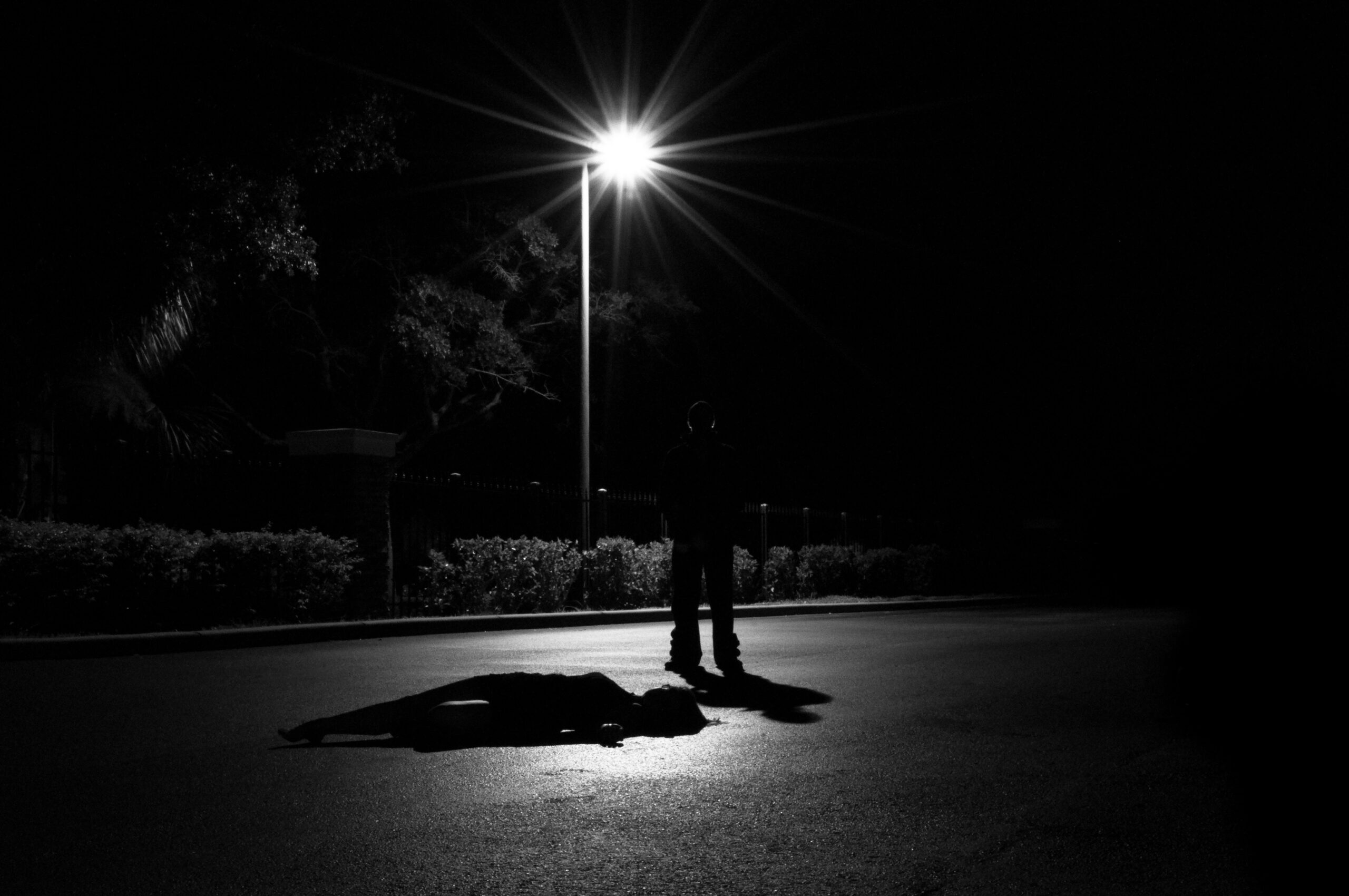 Mann steht im Schatten einer Laterne. Die dunkle Triade