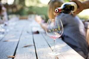 Vom 8. bis 10. August 2025 findet das Weinfest in Münster 2025 auf dem Überwasserkirchplatz statt. Bereits zum 14. Mal veranstalten Severin Romero (gastro.ms) und Weinhandel Trixi Bannert das Fest in unmittelbarer Nähe zum Dom. Das Format bringt Winzerinnen und Winzer aus verschiedenen Regionen zusammen, ergänzt durch ein kulinarisches Angebot und Livemusik an allen drei Tagen. Der Eintritt ist frei. Weinfest in Münster 2025: Veranstaltungsort, Zeiten und Konzept Der Überwasserkirchplatz liegt westlich des Domplatzes und bildet den zentralen Veranstaltungsort für das Weinfest in Münster 2025. Der gepflasterte Platz ist seit 2011 Austragungsort des städtischen Weinfests. Zuvor fand das Fest im Schlossgarten statt. Der neue Standort wurde bewusst gewählt, um einen überschaubaren, stadtintegrierten Rahmen zu schaffen. Die Veranstalter betonen den Fokus auf Qualität, Zugänglichkeit und Atmosphäre. Die Öffnungszeiten sind wie in den Vorjahren: Freitag ab 16 Uhr, Samstag und Sonntag ab 11 Uhr. Die Schlusszeiten orientieren sich am bisherigen Ablauf (Freitag und Samstag bis etwa 24 Uhr, Sonntag bis ca. 20 Uhr), eine offizielle Bestätigung durch die Stadt steht noch aus. Für den Besuch ist keine Anmeldung erforderlich, der Eintritt ist an allen Tagen frei. Weinangebot aus Deutschland, Europa und Südafrika Inhaltlich steht das Weinangebot im Mittelpunkt. Etwa 25 bis 30 Ausstellende – überwiegend Weingüter aus Deutschland – präsentieren vor Ort ihre Produkte. Vertreten sind unter anderem Betriebe aus der Pfalz, von der Nahe, aus Baden und Rheinhessen. Ergänzt wird das Programm durch internationale Anbieter, etwa aus Frankreich, Italien und Südafrika. Alle Stände arbeiten mit einem einheitlichen Glaspfandsystem (voraussichtlich 3 Euro). Die Rückgabe ist an allen Ständen möglich. Zusätzlich werden vor Ort moderierte Verkostungen angeboten. Diese sogenannten Flights umfassen sechs Proben und kosten 12 Euro. Eine Anmeldung ist jeweils bis 30 Minuten vor Beginn am Stand möglich. Kulinarisches Angebot und Rahmenprogramm Neben Wein bildet auch das gastronomische Angebot einen festen Bestandteil des Weinfests in Münster 2025. Erwartet werden Pop-ups regionaler Betriebe mit Speisen wie Flammkuchen, Käseplatten, veganen Gerichten, Burgern und Antipasti. Ziel ist eine bewusste Ergänzung des Weinangebots durch passende, qualitätsorientierte Speisen. Das musikalische Rahmenprogramm steht zum Teil noch aus. Der Veranstalter kündigt jedoch erste Elemente an: Am Freitagabend ist ein Lounge-DJ geplant, am Samstagabend eine mobile Band. Für den Sonntag sind ein Frühschoppen sowie ein Familiennachmittag vorgesehen – inklusive Kinderschminken und Traubensaftbar. Das vollständige Bühnenprogramm wird laut Veranstalter erst kurz vor Veranstaltungsbeginn veröffentlicht. Erreichbarkeit, Bezahlung und Ausstattung Die Veranstaltungsfläche ist barrierefrei zugänglich. Eine rollstuhlgerechte Toilette befindet sich an der Nordseite der Überwasserkirche. Für die Anreise empfiehlt sich die Nutzung des Fahrrads oder öffentlicher Verkehrsmittel. Die Buslinien 14 und 15 halten in unmittelbarer Nähe an der Haltestelle „Tibusstraße“. Für Autofahrer stehen nahegelegene Parkhäuser (Domplatz, Aegidiimarkt) zur Verfügung. Bezahlen können Gäste an den meisten Ständen sowohl mit Karte als auch in bar. Sitzmöglichkeiten sind in Form von Stehtischen, Holzbänken und einer Picknickfläche vorgesehen. Sollte das Wetter umschlagen, stehen Pagodenzelte bereit. Regenschirme werden empfohlen, ein fester Saal steht nicht zur Verfügung.