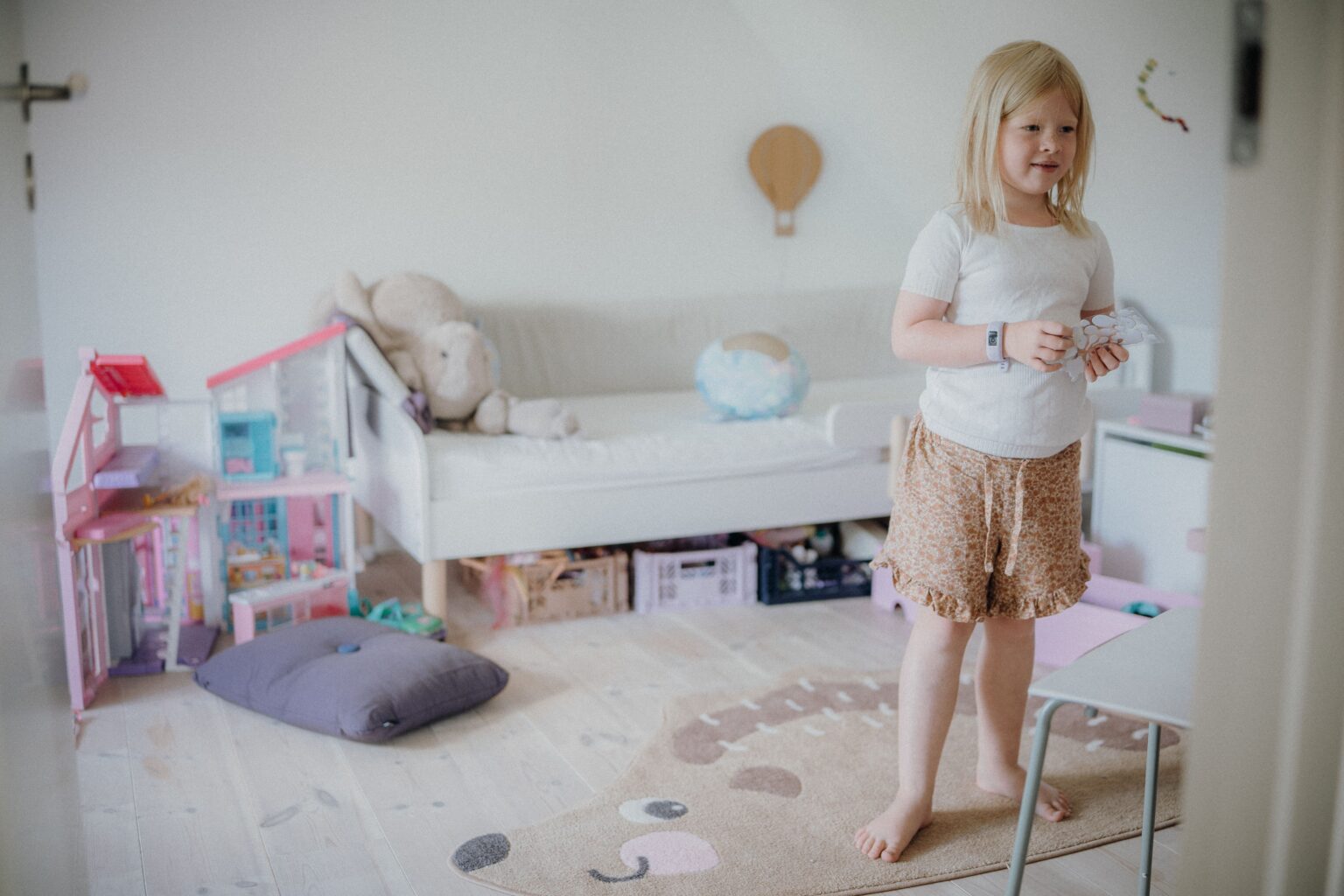 Blondes Mädchen spielt in einem mit Spielzeug gefüllten Kinderzimmer