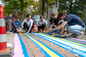 Junge Designerinnen und Designer der Münster School of Design (MSD) der FH Münster gestalteten den ehemaligen Radweg zwischen Dodostraße und Gereonstraße nach Ideen der Anliegerinnen und Anlieger und übermalten das bisher rot gefärbte Pflaster mit bunten Motiven. ©FH Münster / Michelle Liedtke